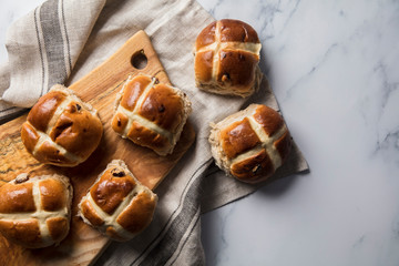 Traditional hot cross buns with raisins on a wooden board