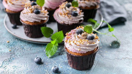 Banner Homemade cupcakes with blueberries on dark blue concrete background.