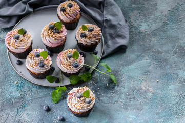 Homemade cupcakes with blueberries on dark blue concrete background.