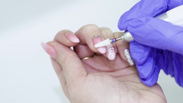Woman makes hardware manicure, removing gel polish