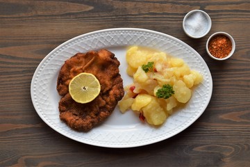 Weiner schnitzel with potato salad on a wooden background