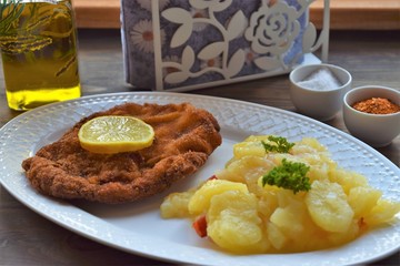 Weiner schnitzel with potato salad on a wooden background