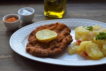 Weiner schnitzel with potato salad on a wooden background