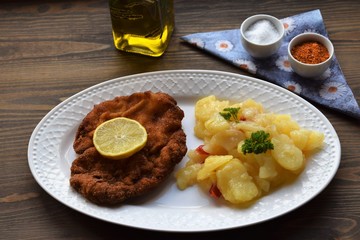 Weiner schnitzel with potato salad on a wooden background
