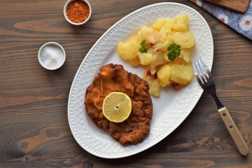 Weiner schnitzel with potato salad on a wooden background