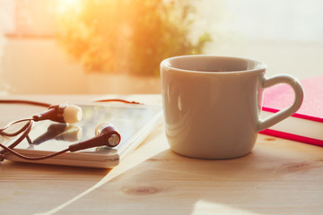 espresso coffee cup, smartphone and earphones on wooden table, morning sunlight, listening to music or audiobook, online education at home