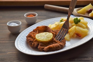 Weiner schnitzel with potato salad on a wooden background