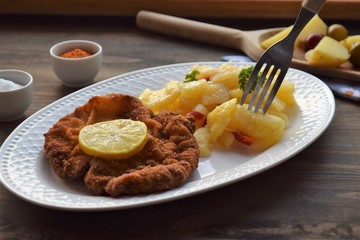 Weiner schnitzel with potato salad on a wooden background