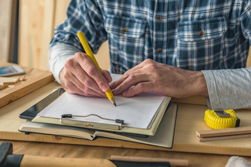 Carpenter writing clipboard notepad project notes and to do list