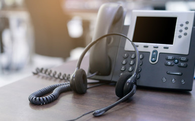 close up soft focus on headset with telephone devices at office desk for customer service support concept	