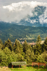 Mountain peak with sun that passes through the clouds. Wooden shelters in the foreground