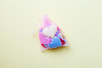 mini textile colorful hearts in transparent bag isolated on yellow background