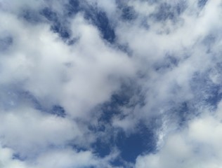 small patches of blue sky peek through white fluffy clouds