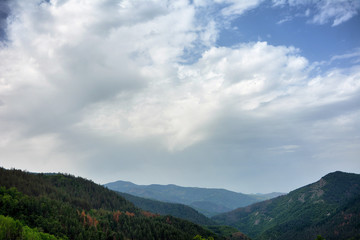 Spring in the mountain with puffy white clouds on sky	
