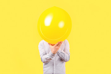 man holding yellow balloon with smile face emotion instead of head. Positive Thinking concepts, image on a yellow background