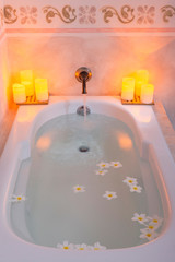 Cozy bathtub with candles and flowers