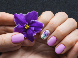 Fashionable lilac manicure design in the hand.