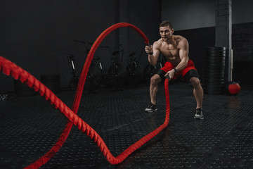 Crossfit battle ropes exercise during atlete training at the workout gym