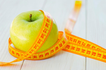 Dieting concept. Green apple with measuring tape. Green apples measured the meter, sports apple