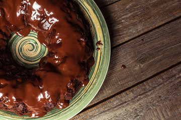 Part of the cupcake drizzled with chocolate on a green plate on wooden table.