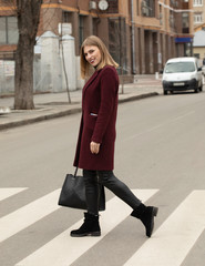 Fototapeta premium Full body portrait of young woman crossing street