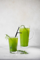 A glass of lemonade tarragon. Carafe in the background.