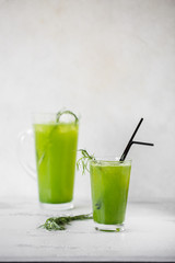 A glass of lemonade tarragon. Carafe in the background.