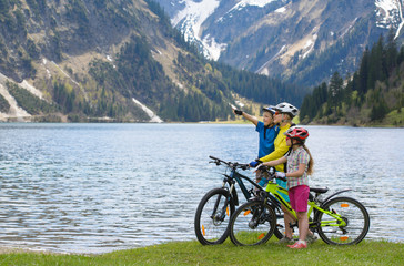 Happy family riding a bike on the lake  in a beautiful mountain landscape.