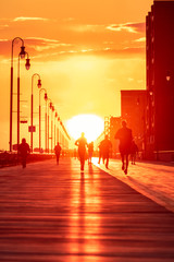 Silhouette of a person running on a boardwalk at sunset. People enjoying outdoor activities under golden light - Long Beach New York