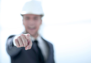 confident engineer in helmet points finger at camera