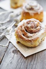 Cinabon rolls with cream cheese and cream, chocolate and almond nuts on wooden background