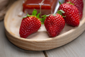 ripe strawberries on a wooden plate with a pack of quincy cheese