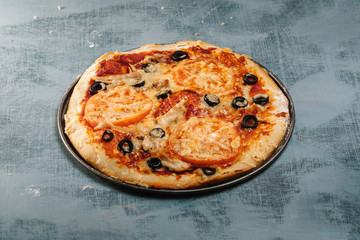 Italian pizza with tomatoes, chicken, olives on wooden background.