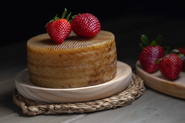 one cheese on a wooden plate with strawberries