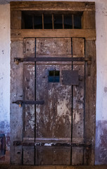Old wooden door with rusty steel door fittings on prison