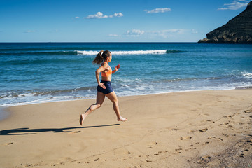 Fitness young woman running on the beach during summer holiday