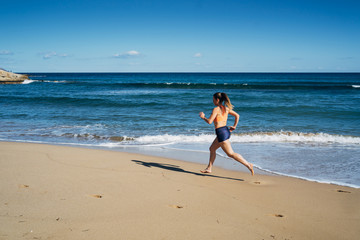 Fototapeta premium Fitness young woman running on the beach during summer holiday