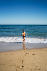 Fitness young woman running on the beach during summer holiday