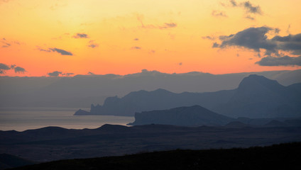 Evening silhouettes of mountains by the sea at sunset in Crimea