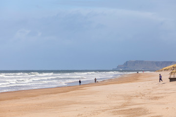 People walking on East Strand Beach, Portrush on a blustery March day