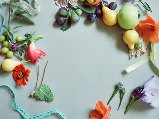 Yellow pears, apples, plums, fresh flowers, leaves, seasonal composition on a light background, top view, empty space in the middle, the concept of summer, harvest, healthy food