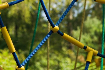 Detail of rope climbing frame  for children.Blue, green and yellow ropes with yellow plastic...