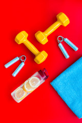 Sport with bars, towel, water and wrist builder red background top view