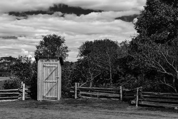  Rustic outhouse next to a fence in Black and white