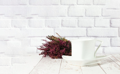 Vintage ceramic white cup  on white wooden background with heather. 