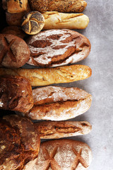 Assortment of baked bread and bread rolls on stone table background