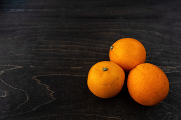 A closeup photo of vibrant organic blood oranges on a dark background with copy space.