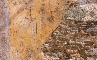 Old, distressed stone wall, building facade. Painted and faded, orange color masonry, texture background