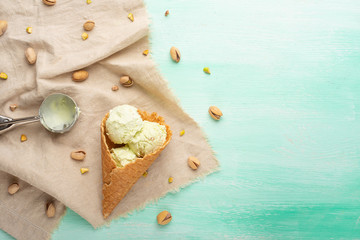 pistachio ice cream cones with pistachios and a spoon for ice cream. On a mint background.Flat lay