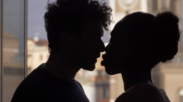 silhouette of mixed couple kissing at the window. interracial love